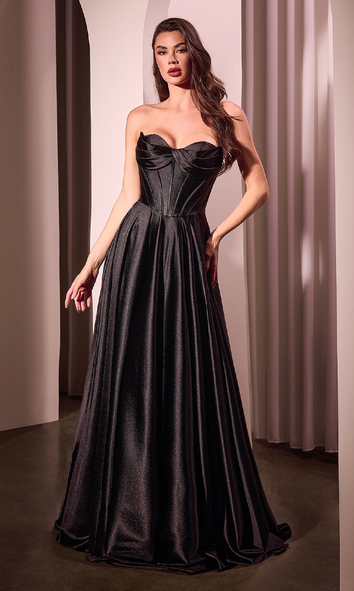 A woman stands indoors wearing the Ladivine CD378 Strapless Long A-Line Prom Dress, featuring a corset-style bodice and full floor-length skirt—an elegant formal evening gown.